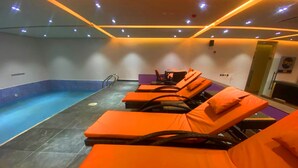 A pool area with multiple orange lounge chairs and a swimming pool. - The Cordis Hotel Ikeja (Lagos)