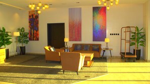 A modern living room with a sofa, armchairs, and a coffee table. There are two lamps, a plant, and a large abstract painting on the wall. - The Cordis Hotel Ikeja (Lagos)