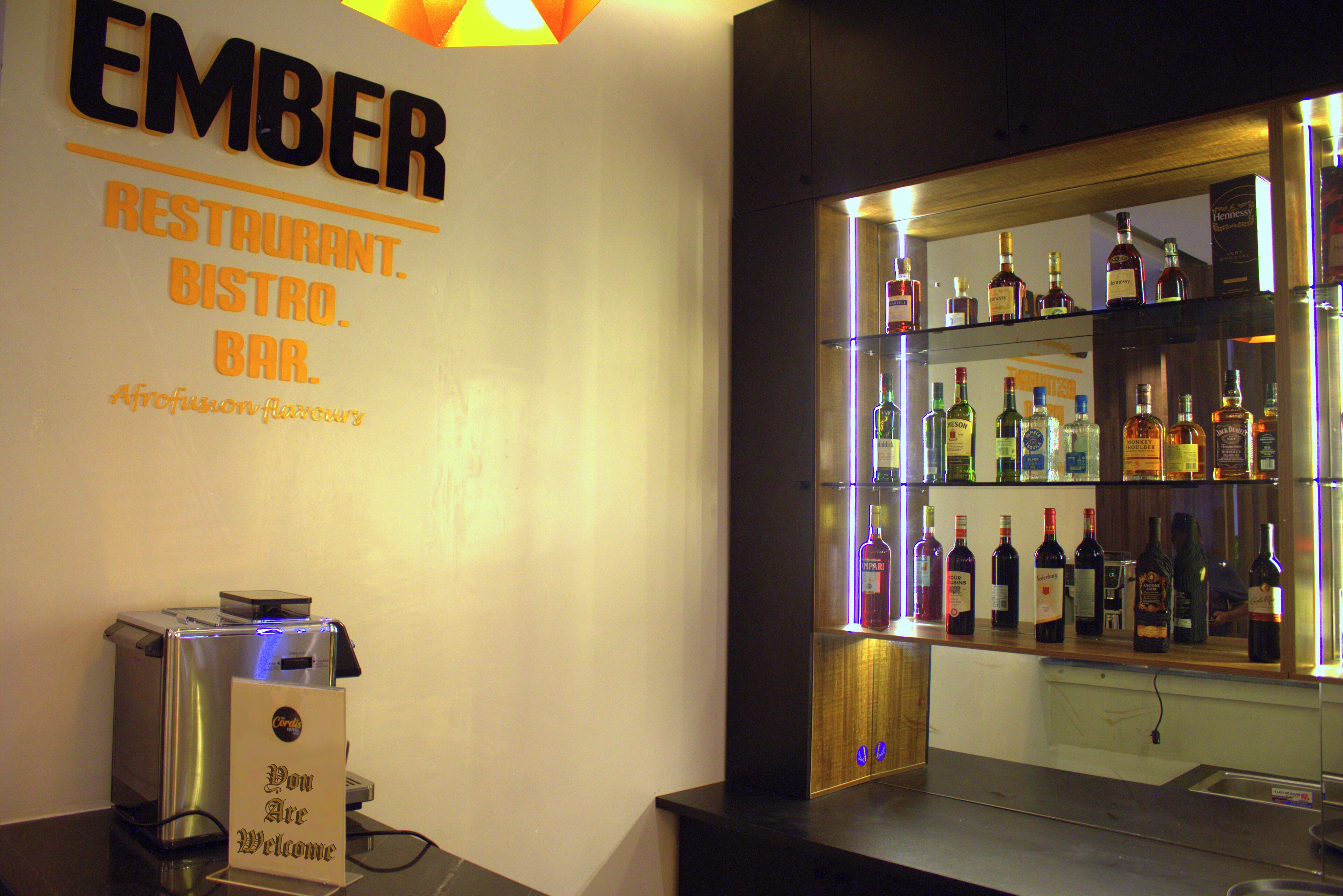 A bar area with a sign reading "EMBER RESTAURANT BISTRO BAR" and a variety of liquor bottles on display.