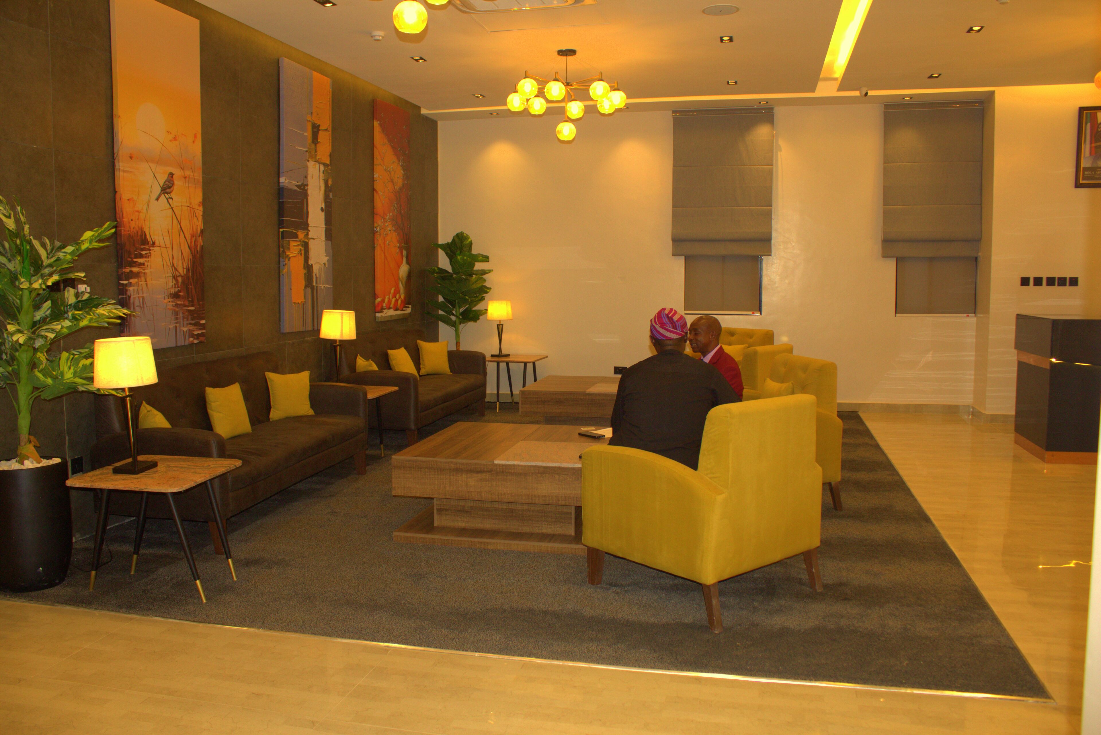 Um hall moderno com um sofá, poltronas, uma mesa de centro e um lustre.
