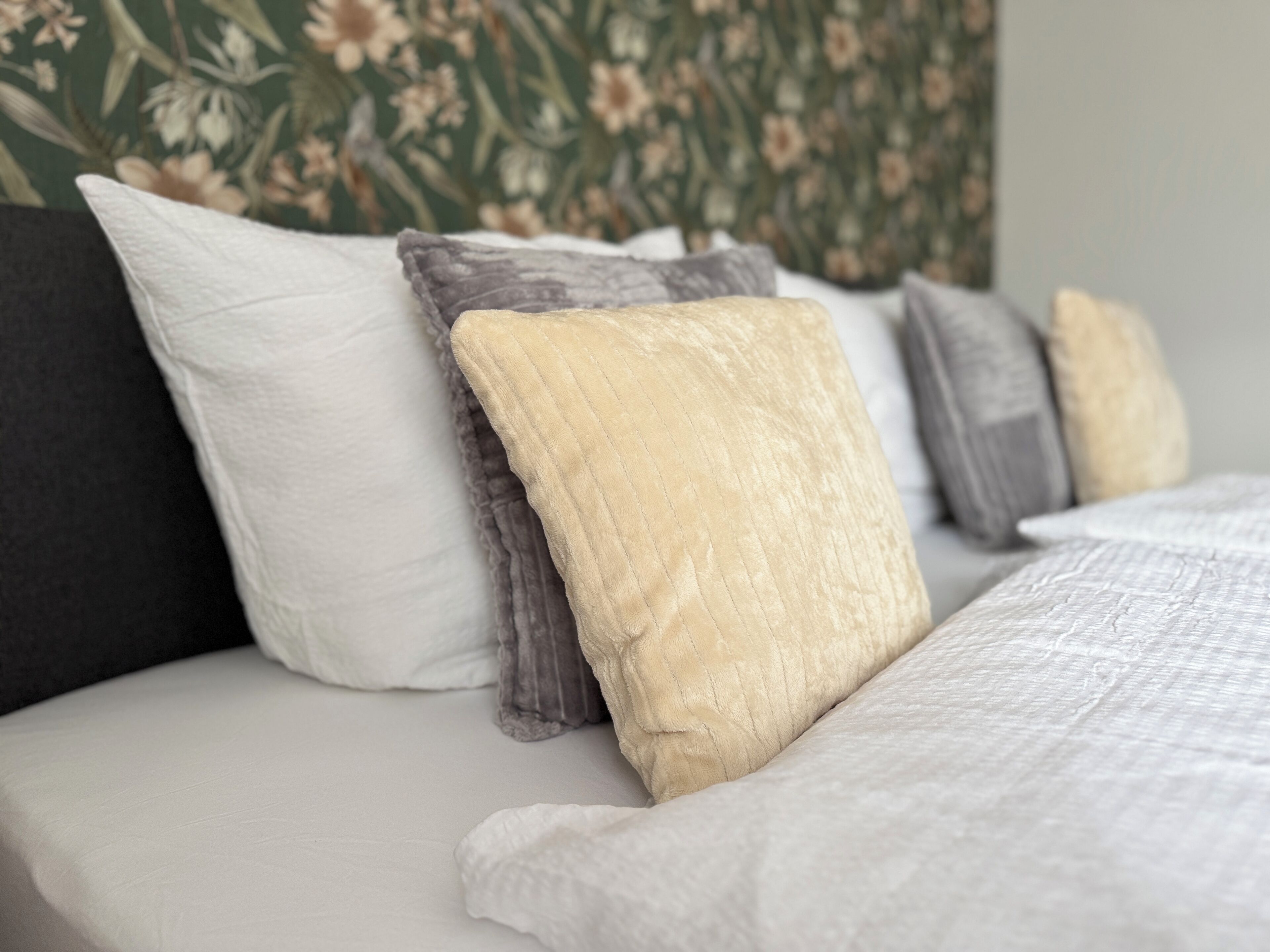 Ein Bett mit vielen Kissen in verschiedenen Farben und Texturen.