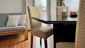 A modern living room with a sofa, a dining table, and a vase with flowers. - Green oasis in Weikersheim, close to the center in a very quiet location. (Weikersheim)