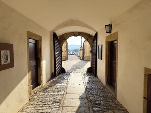A cobblestone pathway leading to a gate, flanked by arched doorways and framed pictures on the walls. - A green oasis in Weikersheim, close to downtown, in a very quiet location. (Weikersheim)