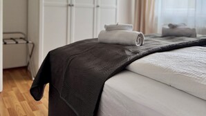 A neatly made bed with a dark blanket and white linens, a white wardrobe, and a window with curtains. - Green oasis in Weikersheim, close to the center in a very quiet location. (Weikersheim)