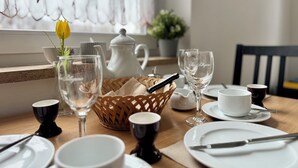 A dining table set with white plates, bowls, and glasses, a white teapot, a wicker basket, and a yellow tulip in a glass vase. - Green oasis in Weikersheim, close to the center in a very quiet location. (Weikersheim)