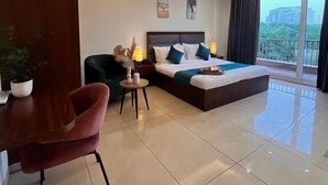 A modern hotel room with a large bed, a desk, and a dining area. - PINK GUAVA HOTELS (Gurugram)