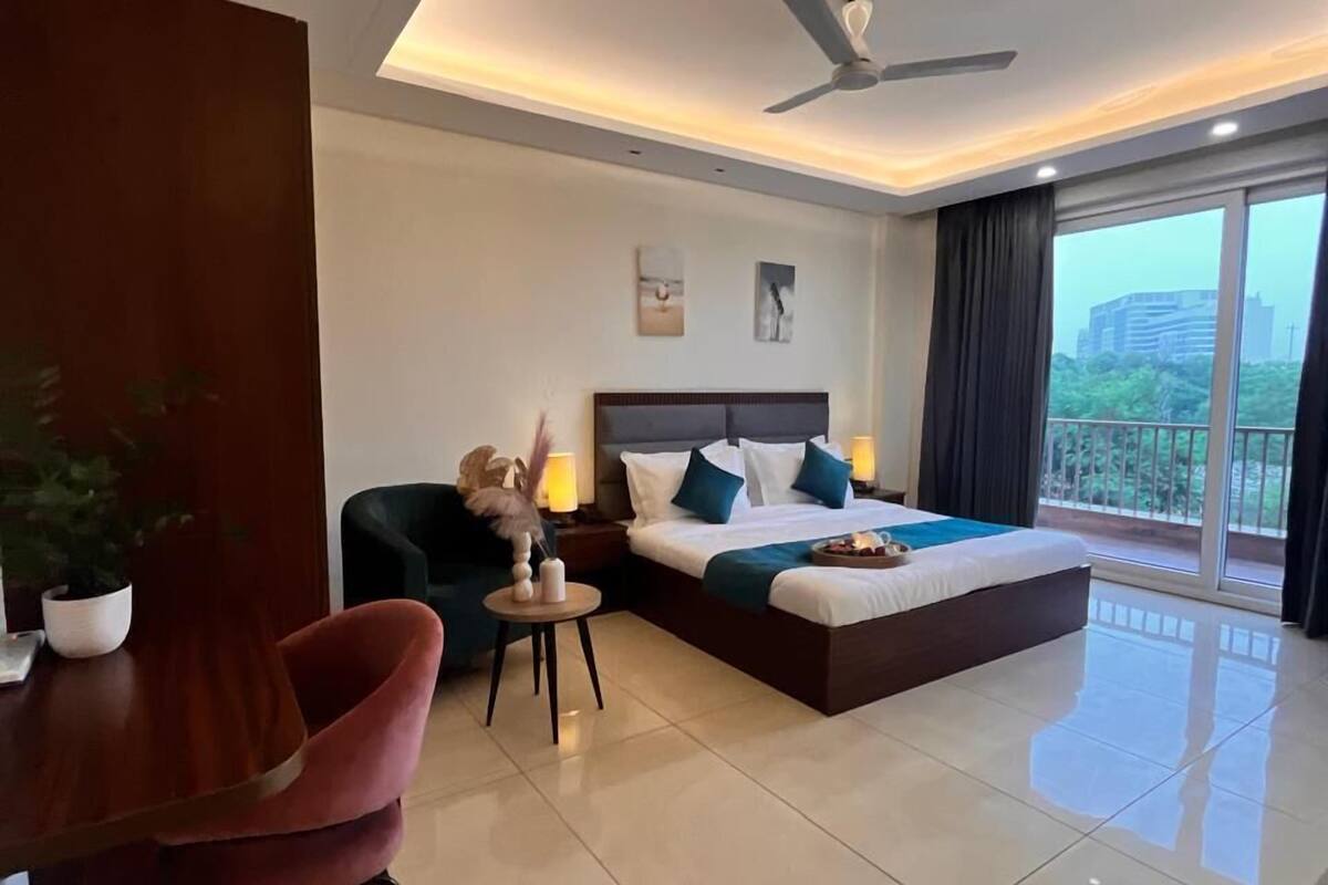 A modern hotel room with a large bed, a desk, and a dining area.