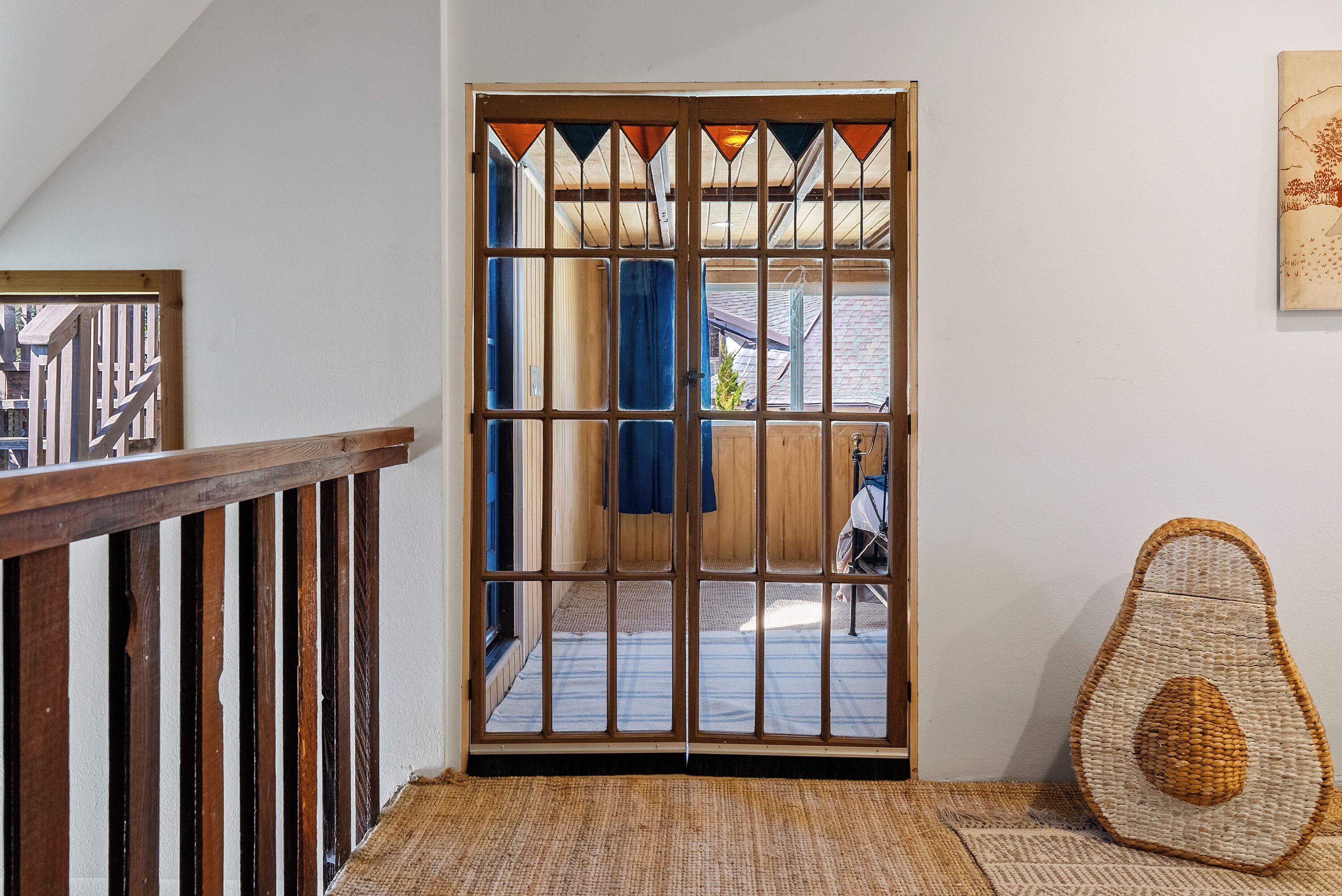 A room with a wooden door, a woven floor mat, and a woven cushion.