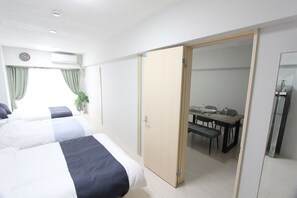 A hotel room with two beds, a dining table with chairs, a small table with a plant, and a sliding door leading to a bathroom. - Shinjuku Kabukicho* 2DK / MAX 10 people / FREE WiFi (新宿区大久保)