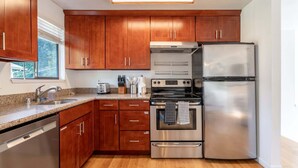 Una cocina moderna con armarios de madera, electrodomésticos de acero inoxidable y un ventanal que proporciona luz natural.