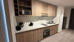 Une cuisine moderne avec des meubles en bois, un plan de travail blanc, un four à micro-ondes encastré, une machine à café et un lave-vaisselle.