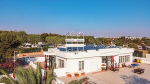 A white building with a sign reading "Atlantide Residence Camping" and solar panels on the roof. - Residence camping Atlantide (Capitolo)