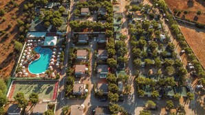 An aerial view of a residential area with a swimming pool, tennis courts, and multiple houses. - Residence camping Atlantide (Capitolo)