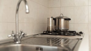 A kitchen with a stainless steel sink, a gas stove, and a pot on the stove. - Residence camping Atlantide (Capitolo)