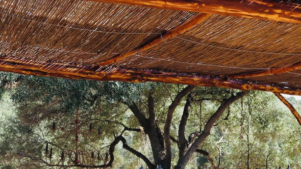 An outdoor patio with a stone fireplace, wooden furniture, and a pergola.
