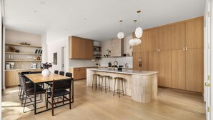 Una cucina moderna con mobili in legno, un'isola centrale con sgabelli e luci a sospensione.