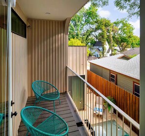 A balcony with two chairs, a wooden fence, and a view of neighboring houses. - Eastside Lux Group Retreat W/ Pool near Downtown (Austin)