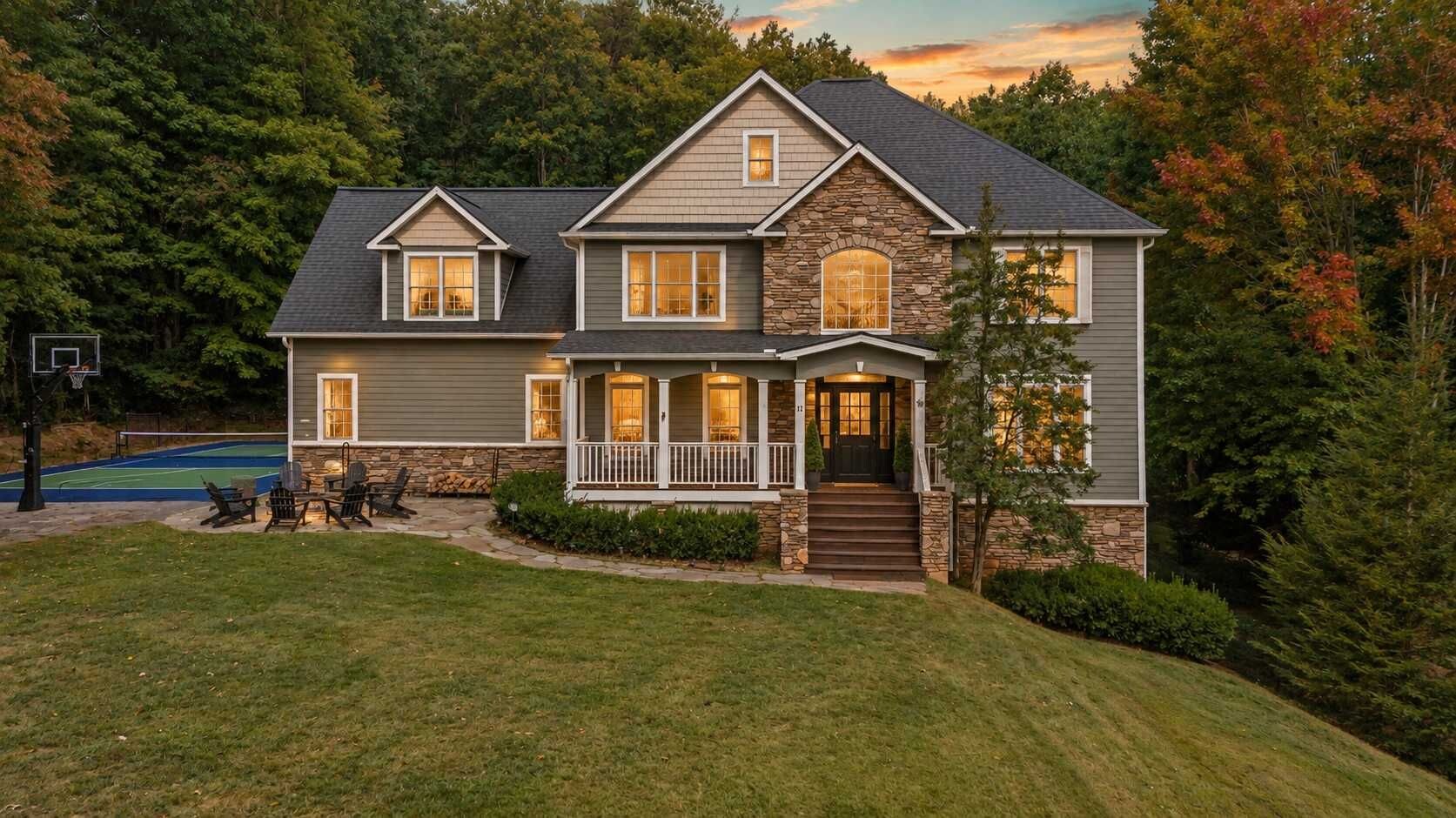 A two-story house with a stone facade, a front porch, and a basketball court.