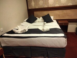 A neatly made bed with a black and white duvet, two black pillows, and a folded towel on the side. - ALJEMEZA TOWER HOTEL (Makkah)