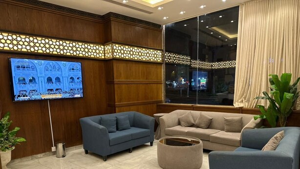 Eine moderne Lobby mit einem großen Fernseher, Sofas und einer Pflanze.