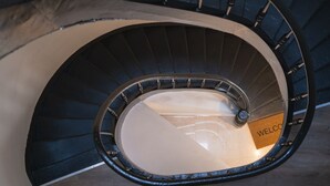 Eine Wendeltreppe mit einem 'WELCOME'-Schild am Fuß.