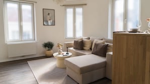 Ein modernes Wohnzimmer mit einem Ecksofa, einem Couchtisch und einer Topfpflanze.