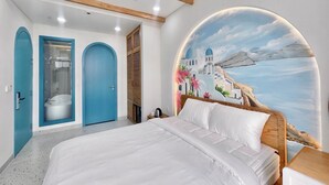 A bedroom with a bed, a bathroom with a bathtub, and a mural of a coastal scene. - Pito Hotel - Hon Thom Phu Quoc (Phu Quoc)