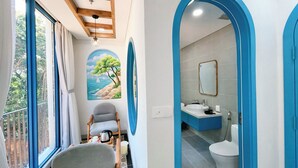 A bathroom with a sink, toilet, and mirror. There is a chair and a table with a kettle and a cup. - Pito Hotel - Hon Thom Phu Quoc (Phu Quoc)