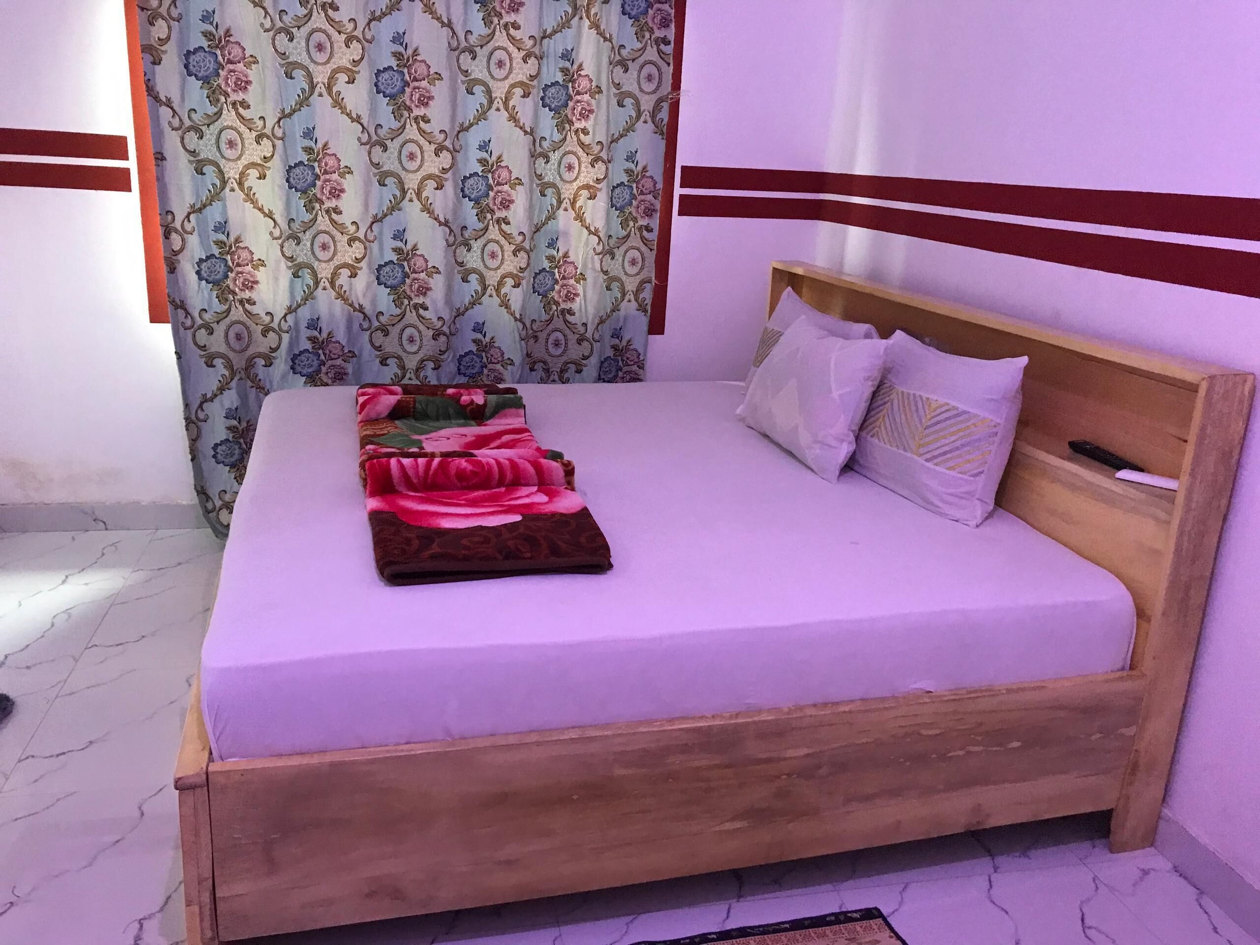 A single bed with a wooden frame, a floral bedspread, and two pillows.