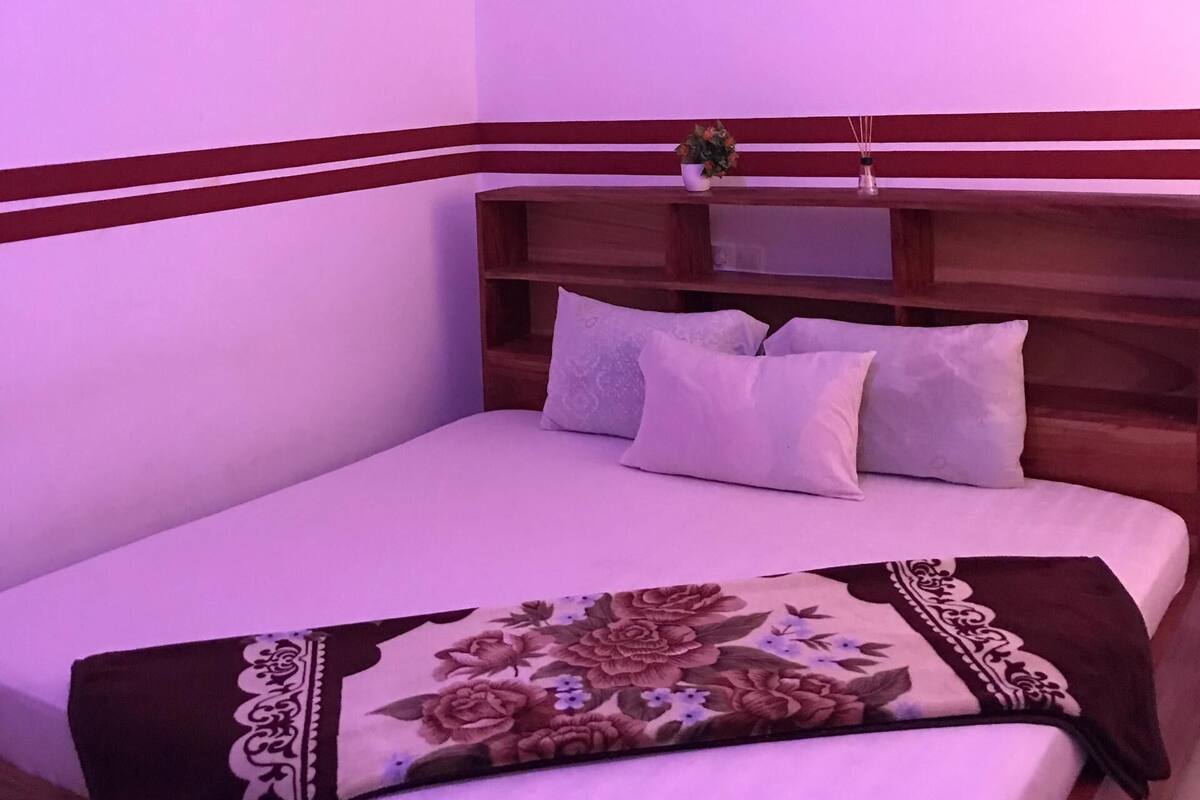 Ein Schlafzimmer mit einem Bett, Kissen, einem Holzkopfende, einem Deckenventilator und einer Klimaanlage.