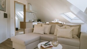Een moderne loft slaapkamer met een schuine kap, een inbouwbed, een kleine keukenhoek en een groot dakvenster.