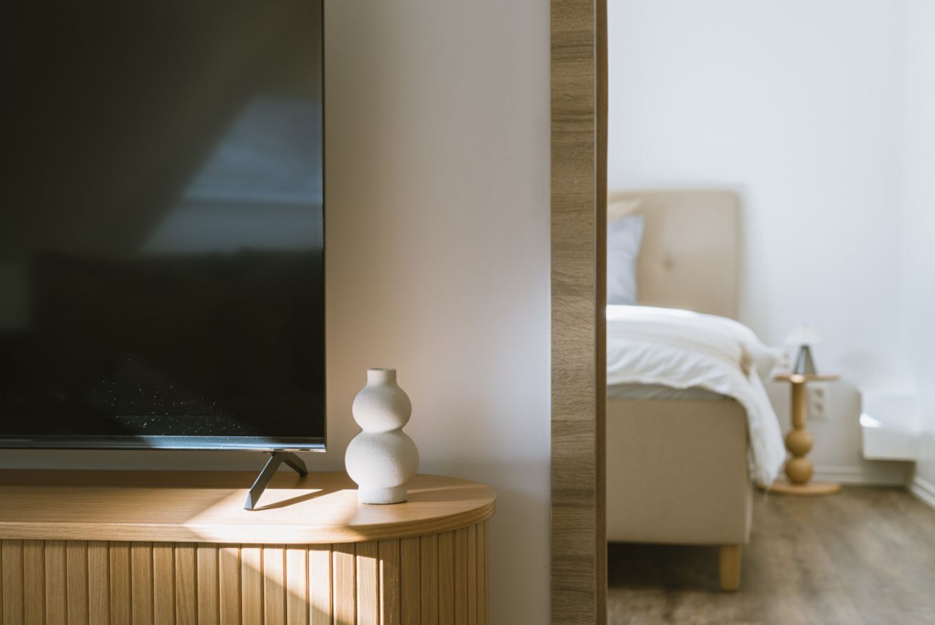 A modern bedroom with a bed, bedside table, and a TV on a stand.