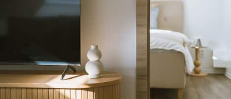A modern bedroom with a bed, bedside table, and a TV on a stand.