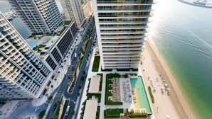 Un hôtel de grande hauteur, avec de nombreux étages, une piscine et une vue sur la plage.