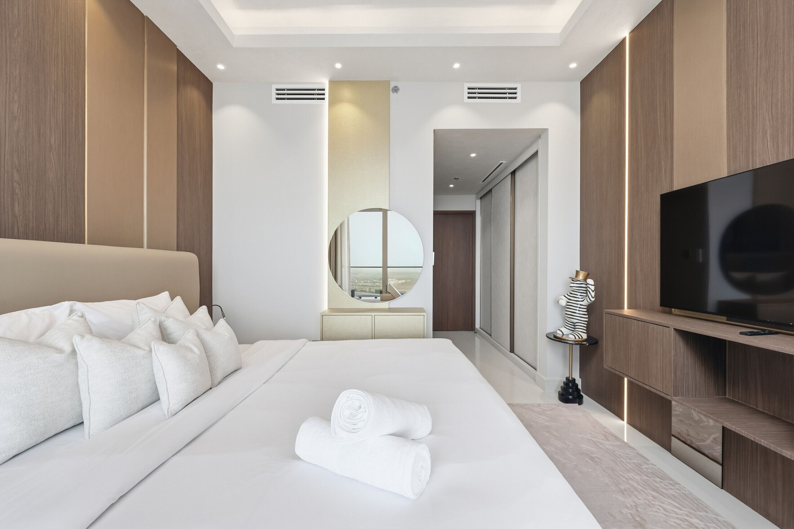 Una habitación de hotel moderna con una cama grande, un televisor de pantalla plana y vistas a través de una puerta.