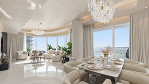 Un vaste salon comprenant un coin repas, de grandes fenêtres et une vue sur la ville.