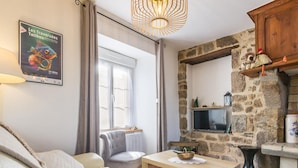 Una sala de estar acogedora con un sofá, una mesa con una cesta, una chimenea de piedra y un cartel en la pared.