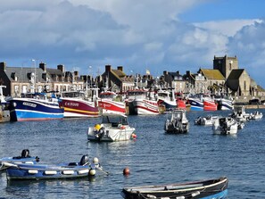 A harbor with various boats docked, a prominent church tower, and a row of buildings along the waterfront.