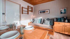 Una cocina acogedora con armarios de madera, una mesa de comedor con platos y vasos, un sofá con cojines y un cuadro en la pared.