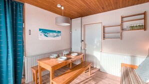 Un comedor acogedor con una mesa de madera preparada para cuatro personas, un banco e iluminación colgante.
