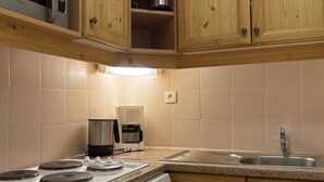Une cuisine avec des meubles de rangement en bois, une cuisinière, une machine à café et un lave-vaisselle.