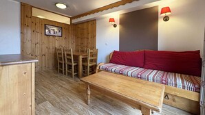 Une pièce chaleureuse avec une table à manger en bois, un banc doté de coussins rouges et deux lampes fixées au mur.