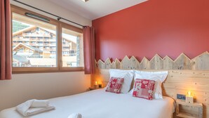 Habitación de hotel con una cama grande, cabecero de madera y vista a un edificio desde la ventana.