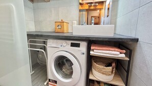 A compact laundry area with a washing machine, a sink, and a mirror. - 3-room apartment in Praz-Sur-Arly, 6 people, parking, near slopes (Praz-sur-Arly)
