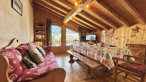 A cozy wooden interior with a sofa, dining table, and benches. - 3-room apartment in Praz-Sur-Arly, 6 people, parking, near slopes (Praz-sur-Arly)