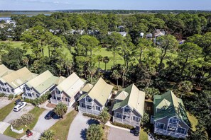 A residential area with multiple houses, a golf course, and a body of water in the background.