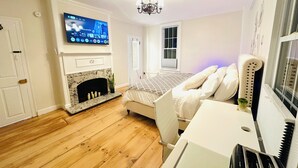 A bedroom with a TV, fireplace, bed, and a piano. - Liz Room in downtown Exeter next to PEA (Exeter)