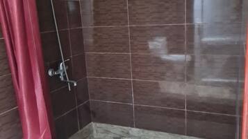 A shower area with dark brown tiles, a red shower curtain, and a metal shower head.