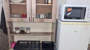 A compact kitchen with wooden cabinets, a microwave, a refrigerator, and a sink.