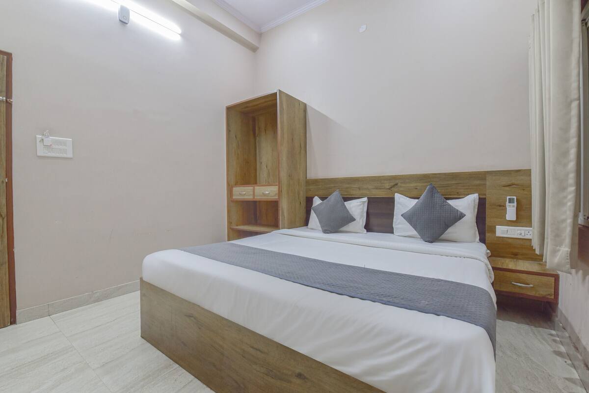 A neatly arranged bedroom with a wooden headboard, a bed with white bedding, and a bedside table with a lamp.